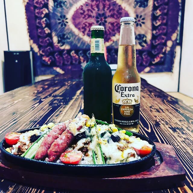 野菜とソーセージが盛られた鉄板料理とボトルビール